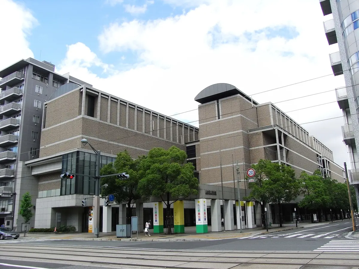 The modern front of a museum building with flower beds before it
