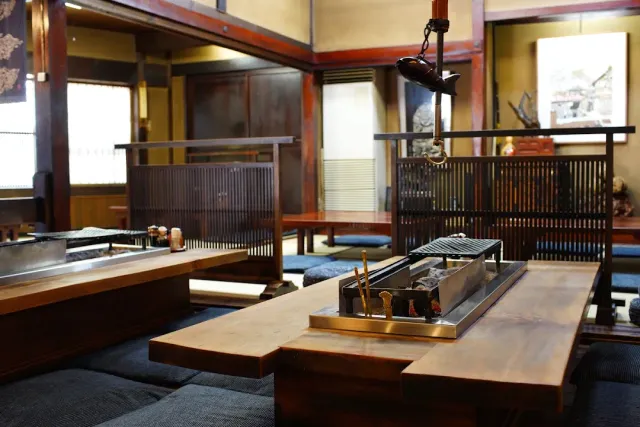 A hall with low tables, a hearth sunk into the table, a hanging kettle and wooden partitions