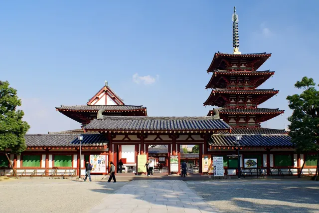 A red temple gate with a five-storey pagoda behind it