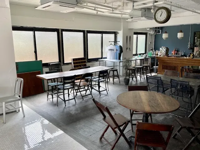 A room with a long table, mixed chairs, a wall clock and a counter at the side