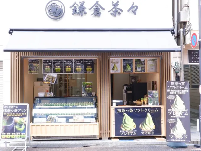 A small shop with a white awning, a display fridge and green ice cream posters at the entrance