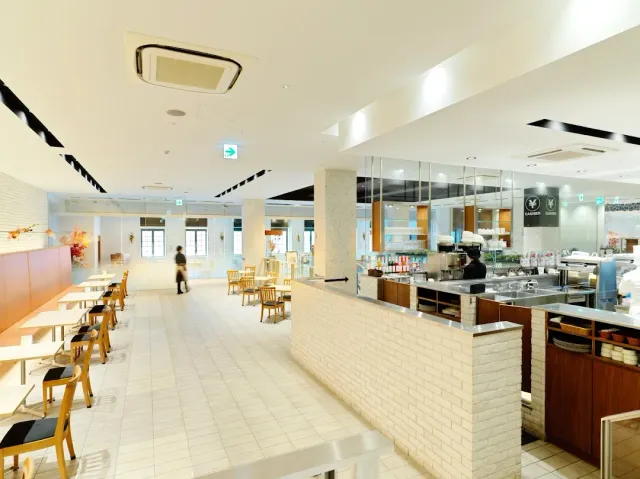A bright spacious hall with a white brick counter, light tables and a high ceiling