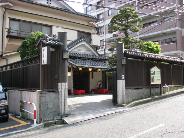 A traditional restaurant building with a dark wall and wooden fence on a quiet street