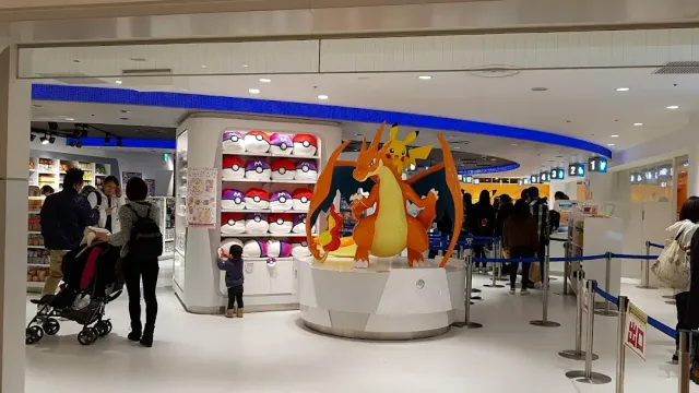 A brightly lit store with an orange dragon character statue in the center and shelves of plush toys around