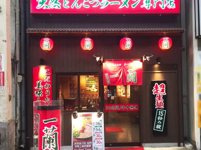 A frontage with a large red sign, four red lanterns and banners in Japanese script