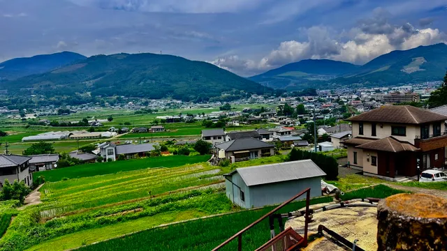 A view from above over a valley with rice fields, houses and green mountains