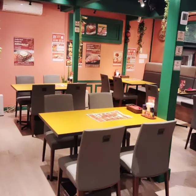A hall with yellow tables, green posts and orange walls with dish posters