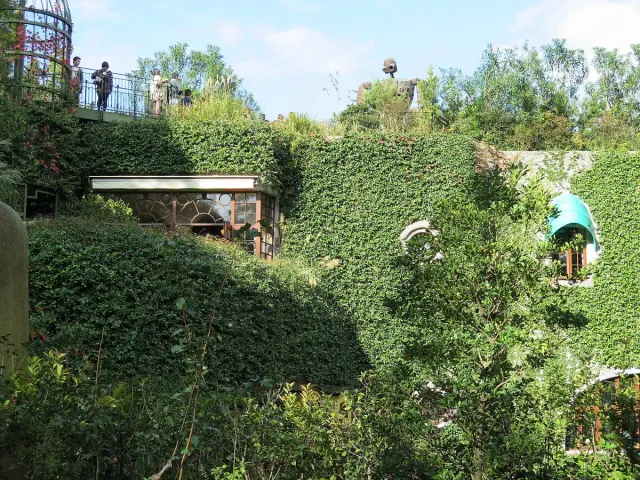 A building covered in green ivy with a round rooftop terrace