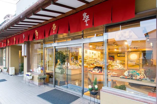 A shopfront with red fabric curtains and lit display windows holding products