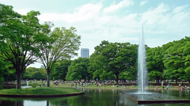 A tall fountain in a pond, with lawn and visitors around it