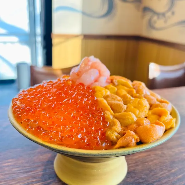 A footed bowl with orange fish roe on one side and yellow sea urchin on the other