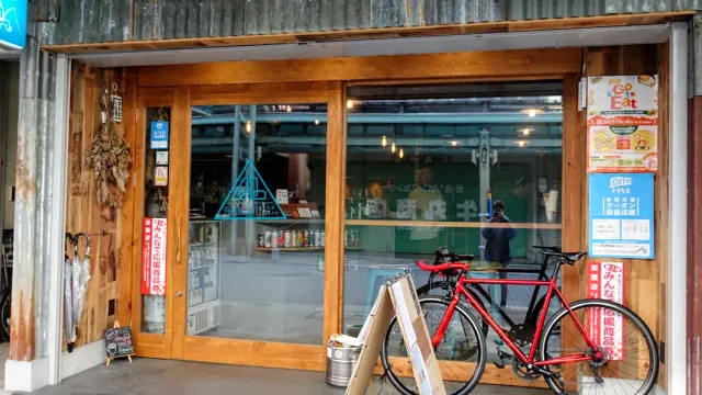 A facade with a wooden frame and a wide window, with a red bicycle parked beside it