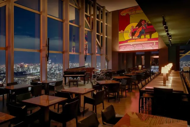 A high floor hall with huge windows, a grand piano and a night city view