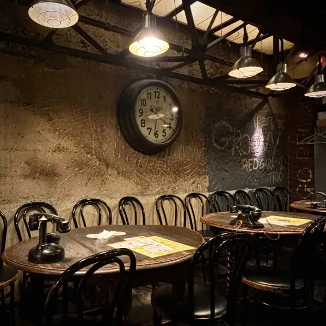 Round tables and bentwood chairs, a large wall clock and hanging lamps