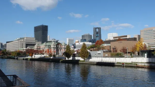 A wide river between landscaped banks with office towers behind
