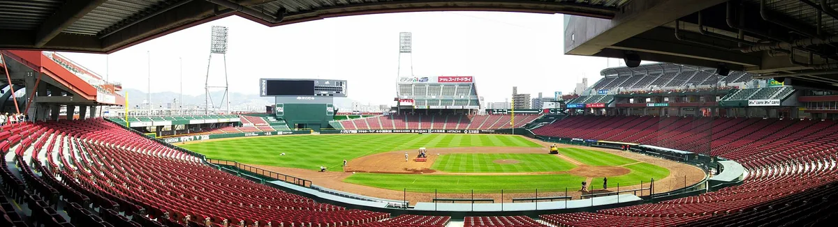Empty red stands around a green baseball field