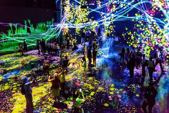 A dark room flooded with colourful lines of light across floor and walls
