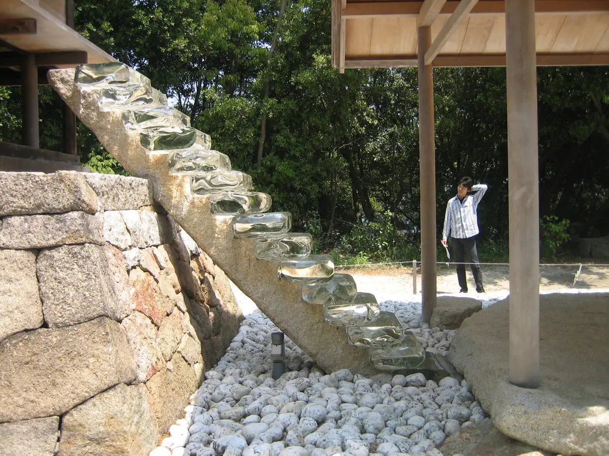 Transparent glass stairs descending an old stone wall into an underground stone structure, part of Go'o Shrine in the Honmura Art House Project