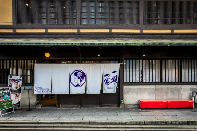 A traditional wooden house front with white cloth curtains and thin wooden lattices