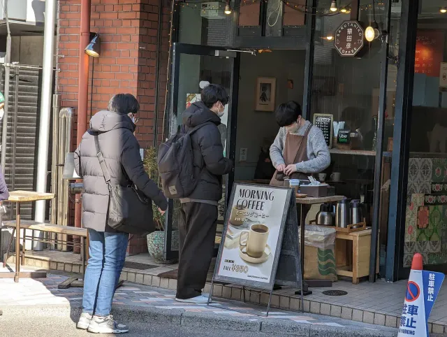 Customers standing at a small coffee counter on a street corner