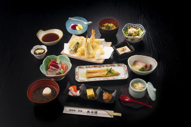 A Japanese meal in small bowls on a dark table, with tempura, sashimi and soup