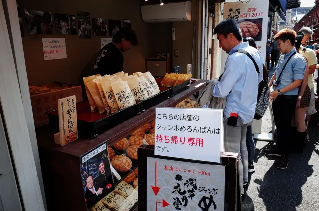 A sales counter with wrapped buns and waiting customers