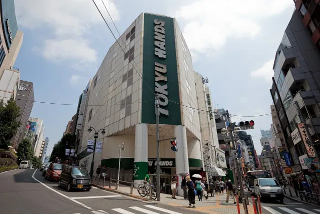 A green department store building at a busy city junction