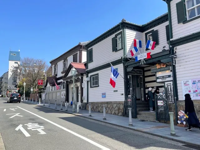 A street with western style wooden houses, flags on the facade and blue sky
