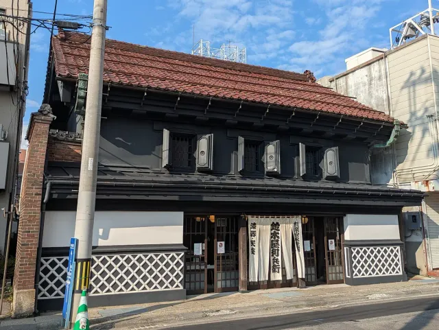 A traditional shop building with dark walls and a tiled roof