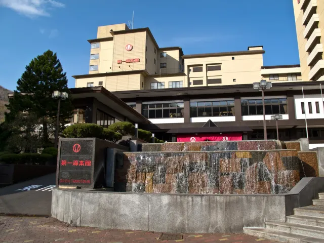 A large bathhouse hotel on a slope with a rock wall in front