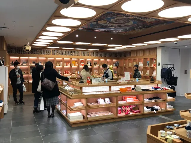 A shop interior with wooden shelves, round ceiling lights and shoppers by a display table