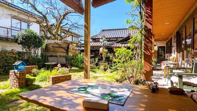 A wooden table under an eave, facing a garden and houses with tiled roofs