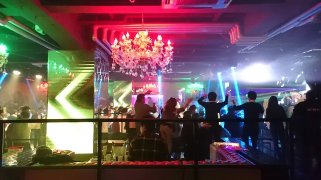 A dance floor with pink and blue lights, a large chandelier and a dancing crowd