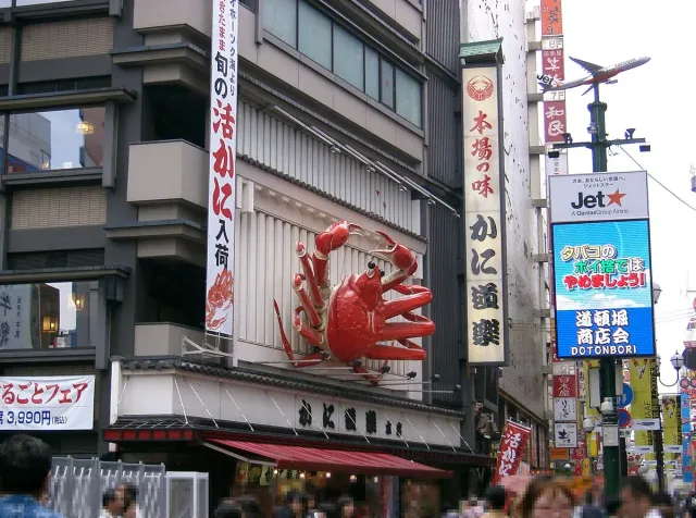 A giant red crab sign on a restaurant front among neon signage