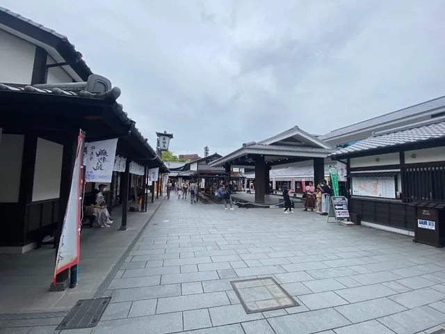 A stone paved street between traditional wooden buildings with tiled roofs and hanging banners