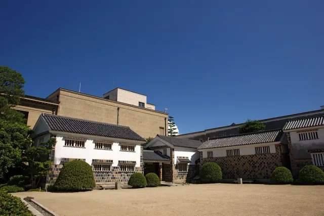 A white museum building with columns, surrounded by clipped hedges
