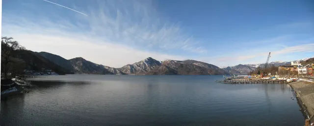 A wide, still lake at the foot of a dark mountain ridge