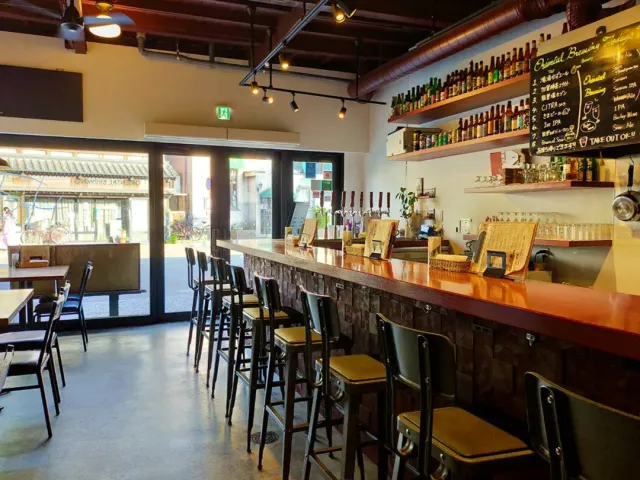 A long orange counter with tall stools, beer taps and a bottle shelf