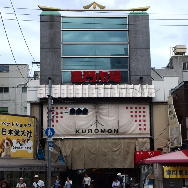 The front of a covered market with a large sign and shops on both sides