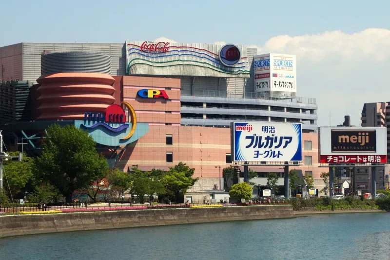 A curved shopping complex in red and orange tones along a water canal