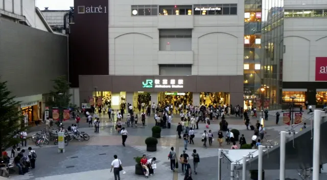 A busy station exit with signage and lit buildings