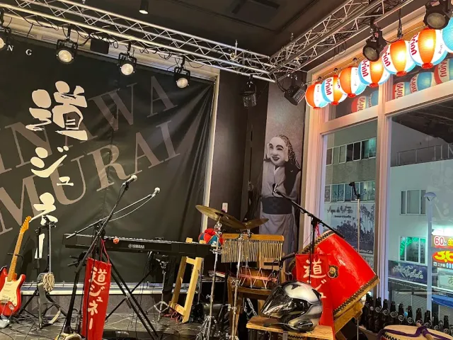 A small stage with drums, a keyboard, a cloth banner and colourful paper lanterns