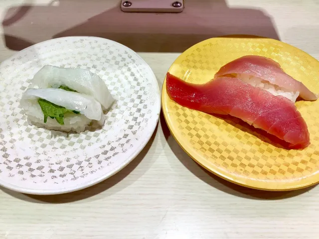 Two plates of sushi, one with red fish and one with white