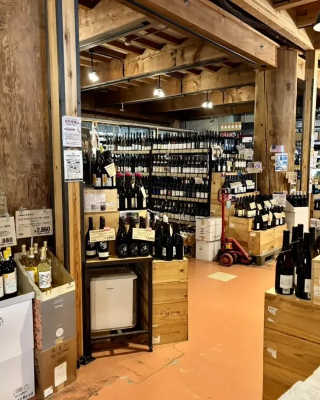 A wooden warehouse with shelves loaded with wine bottles and wooden crates on the floor