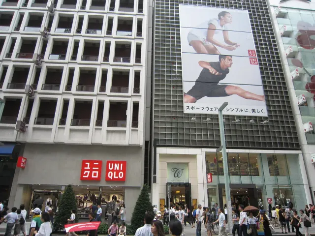 A multi-storey flagship store front with red signage and passers-by