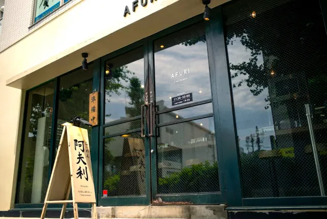 A shop with dark framed glass doors and a folding wooden sign on the pavement