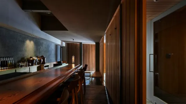 A narrow space with a long wooden counter, stools and panelled walls