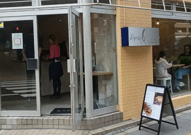 An open glass entrance with a worker at the counter and a menu board outside