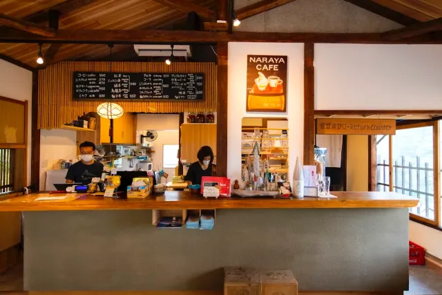 A wooden counter with two staff, a chalk menu in Japanese and a beamed ceiling