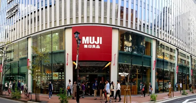 A corner shopfront with a large red sign, passersby on the sidewalk
